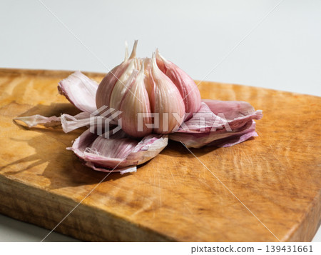 Fresh garlic bulb with pink skin on a wooden cutting board Fresh garlic bulb with pink skin on a wooden cutting board 139431661