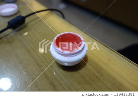 Small Container with Red Substance on Wooden Surface Small Container with Red Substance on Wooden Surface 139432391