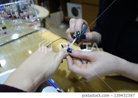 Nail Technician Applying Polish to Client's Nail 139432397