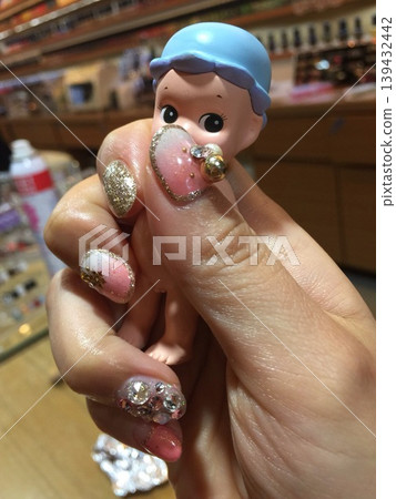 Hand with Glitter Nail Art Holding Miniature Doll Hand with Glitter Nail Art Holding Miniature Doll 139432442