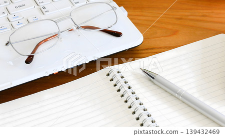 A simple desk scene with a notebook and glasses. A simple desk scene with a notebook and glasses. 139432469