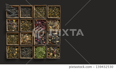Collection of various loose tea leaves arranged on wood with vibrant petals and textured leaves 139432530