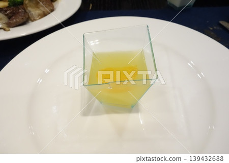 Glass Container with Yellow Liquid on Plate Glass Container with Yellow Liquid on Plate 139432688