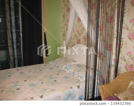 Floral Bed in Cozy Bedroom with Wallpaper and Wicker Chair 139432766