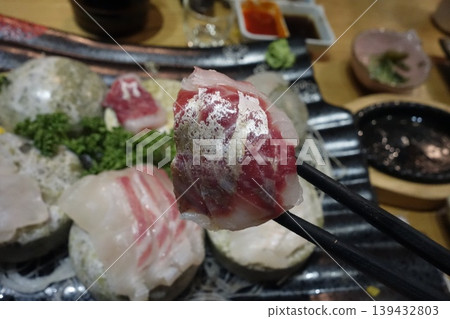 Sushi Piece Held by Chopsticks Over Platter Sushi Piece Held by Chopsticks Over Platter 139432803