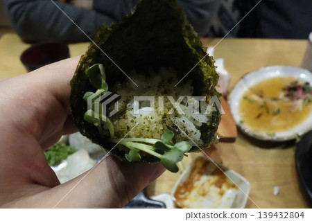 Hand Holding Seaweed-Wrapped Rice Snack with Sprouts Hand Holding Seaweed-Wrapped Rice Snack with Sprouts 139432804
