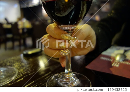 Hand Holding Wine Glass with Glitter Nails in Restaurant 139432823