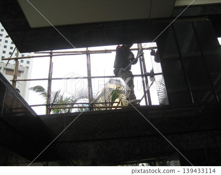 Construction Workers on Scaffolding at Urban Building Site 139433114