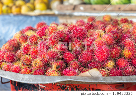 Abundant Pile of Tropical Fruit in a Rustic Container, Showcasing Vibrant Red and Yellow Hues with Hairy Textures. Sri Lanka island in Asia. Abundant Pile of Tropical Fruit in a Rustic Container, Showcasing Vibrant Red and Yellow Hues with Hairy Textures. Sri Lanka island in Asia. 139433325