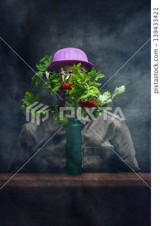 A man in a hat behind red viburnum branches A man in a hat behind red viburnum branches 139433421