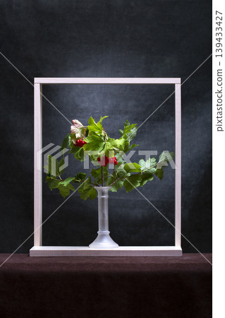 A branch of red viburnum in a vase and a wooden frame 139433427
