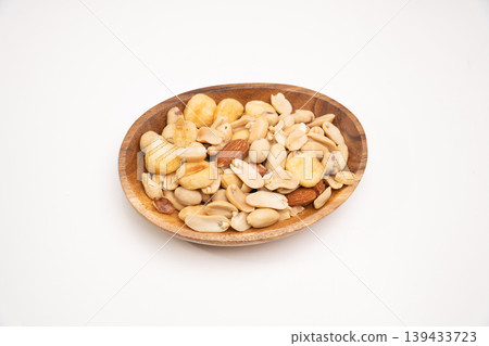 Close-up of a wooden plate and nuts on a white background Close-up of a wooden plate and nuts on a white background 139433723