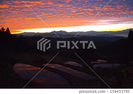 The dawn over the terraced rice fields of Echigo Satoyama, bathed in the morning light. The dawn over the terraced rice fields of Echigo Satoyama, bathed in the morning light. 139433795