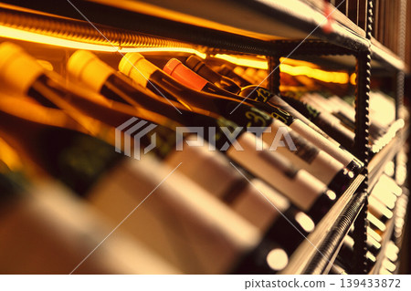 Golden-lit wine bottles on metal rack 139433872