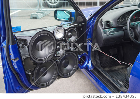 Custom car audio system with multiple speakers installed in blue vehicle door panel interior 139434355