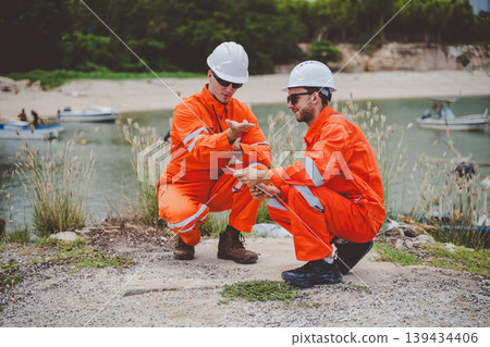 Oil and gas engineers discussing technical data at site near coastal refinery Oil and gas engineers discussing technical data at site near coastal refinery 139434406
