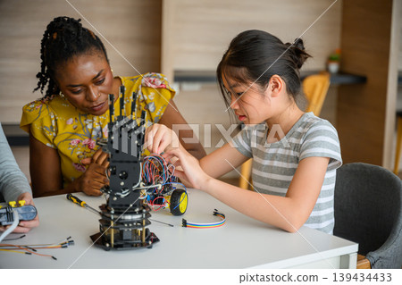 Mentor instructing student assembling robotic hand and wiring electronics in STEM class Mentor instructing student assembling robotic hand and wiring electronics in STEM class 139434433