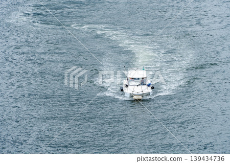 An overhead view of a small boat leaving a wake on the water's surface. An overhead view of a small boat leaving a wake on the water's surface. 139434736