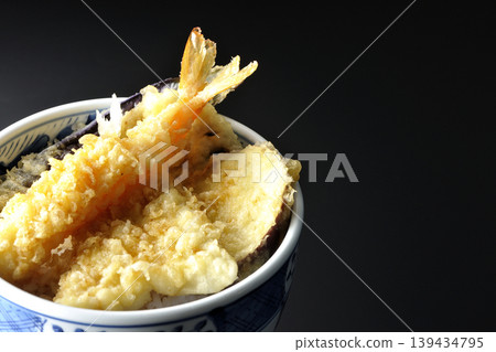 Tempura rice bowl photographed alone against a black background. Tempura rice bowl photographed alone against a black background. 139434795
