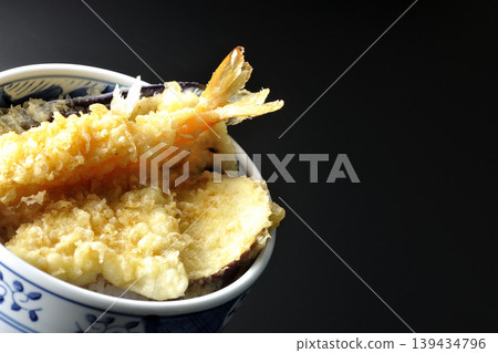 Tempura rice bowl photographed alone against a black background. Tempura rice bowl photographed alone against a black background. 139434796