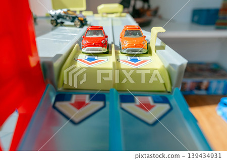 Toy cars placed on racing track ready to start. Children play concept and imagination development at home. Toy cars placed on racing track ready to start. Children play concept and imagination development at home. 139434931