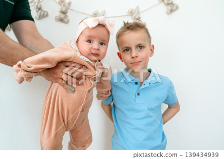 Young boy standing next to baby 4 month sibling held by parent. Family, care and childhood concept. 139434939