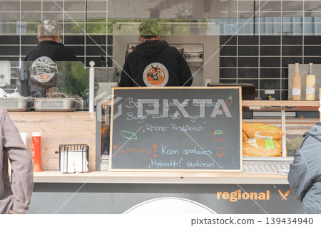 Street food truck counter with menu board. Urban lifestyle and fast food service concept. Outdoor food stand with customers. Street cuisine and city life atmosphere. Street food truck counter with menu board. Urban lifestyle and fast food service concept. Outdoor food stand with customers. Street cuisine and city life atmosphere. 139434940
