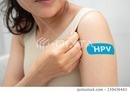 HPV, Human papillomavirus, Asian young woman receiving vaccine with blue bandage. HPV, Human papillomavirus, Asian young woman receiving vaccine with blue bandage. 139436483