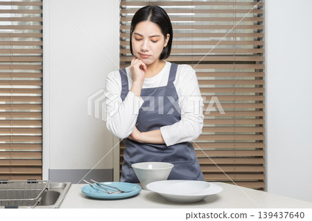 A lifestyle image of a young woman standing in the kitchen. A lifestyle image of a young woman standing in the kitchen. 139437640