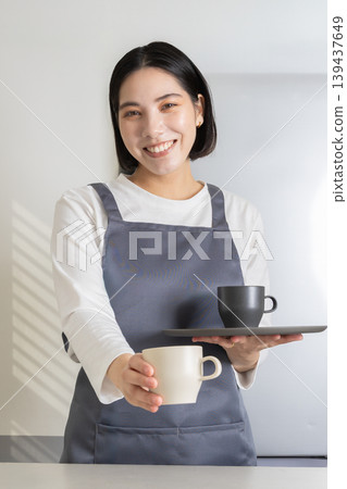 A lifestyle image of a young woman standing in the kitchen. A lifestyle image of a young woman standing in the kitchen. 139437649