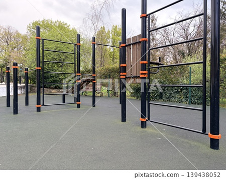 An open sports ground with a soft surface and metal horizontal bars for sports activities 139438052