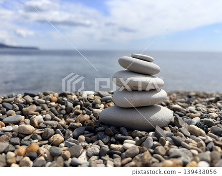 a serene, low-angle close-up of five smooth, light-grey stones carefully stacked in perfect balance on a pebble beach. A miniature cairn or zen tower. a serene, low-angle close-up of five smooth, light-grey stones carefully stacked in perfect balance on a pebble beach. A miniature cairn or zen tower. 139438056