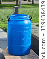 Empty blue plastic barrel standing on a wooden pallet outdoors. Industrial waste storage container for gardening or transport. Reusable material supply unit for exterior site work. 139438439