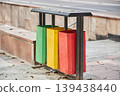 Metal recycling bin with three containers for waste sorting. Outdoor trash can for selective garbage separation. Environmental protection and sustainability concept for city street trash management. 139438440