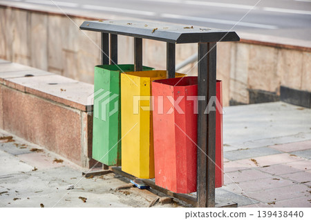 Metal recycling bin with three containers for waste sorting. Outdoor trash can for selective garbage separation. Environmental protection and sustainability concept for city street trash management. Metal recycling bin with three containers for waste sorting. Outdoor trash can for selective garbage separation. Environmental protection and sustainability concept for city street trash management. 139438440