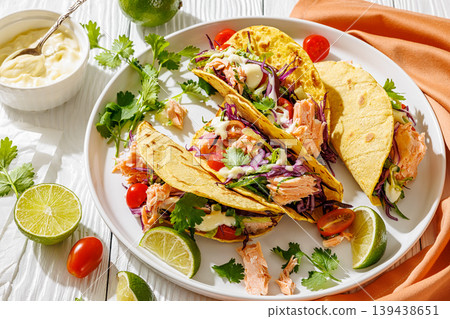 salmon tacos drizzled with sauce on a plate salmon tacos drizzled with sauce on a plate 139438651