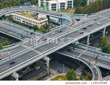 Multilevel highway interchange with numerous vehicles traversing elevated roads and ramps in a dense city environment Multilevel highway interchange with numerous vehicles traversing elevated roads and ramps in a dense city environment 139439086