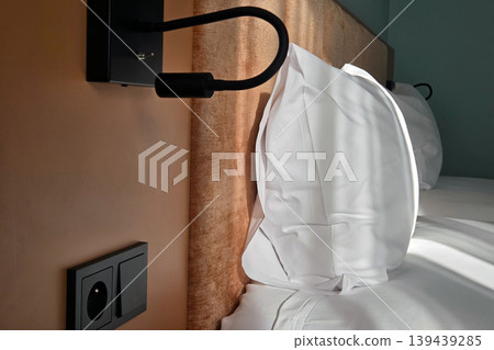 Cozy Hotel Bedroom with Modern Wall Light and Soft Pillows for Relaxation and Comfort Cozy Hotel Bedroom with Modern Wall Light and Soft Pillows for Relaxation and Comfort 139439285
