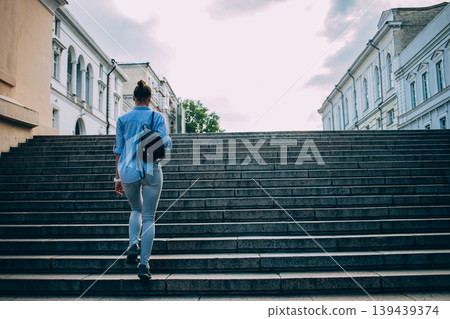 Person walks up large stone staircase in urban environment Person walks up large stone staircase in urban environment 139439374