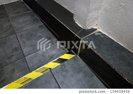 Yellow Caution Tape on Floor Near Corner and Wall for Safety and Hazard Awareness Yellow Caution Tape on Floor Near Corner and Wall for Safety and Hazard Awareness 139439456