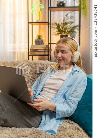 Young woman freelancer relaxed on couch, laptop work, cozy home comfort, sunset vibe, creative flow Young woman freelancer relaxed on couch, laptop work, cozy home comfort, sunset vibe, creative flow 139439541