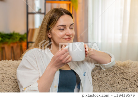 Happy woman drinking tea at home in the morning, calm expression, peaceful and relaxing moment 139439579