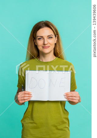 Adult woman proudly showing notebook page with big word done written after completing important task Adult woman proudly showing notebook page with big word done written after completing important task 139439606
