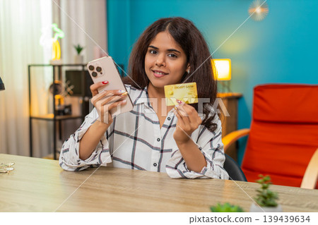 Indian woman reviewing credit card numbers on smartphone before payment online purchase process safe Indian woman reviewing credit card numbers on smartphone before payment online purchase process safe 139439634