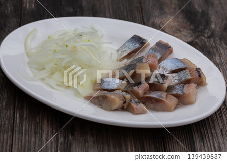 Salted herring with onions on a white plate, the perfect appetizer for vodka. Salted herring with onions on a white plate, the perfect appetizer for vodka. 139439887