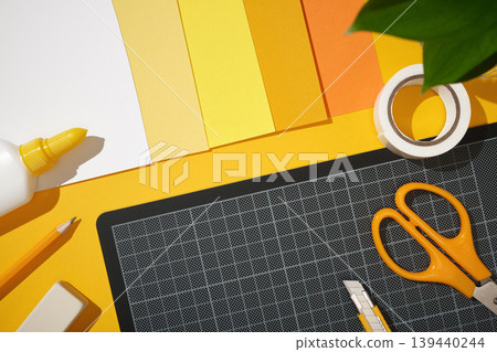 Workspace for paper crafts. Scissors, glue, a pencil, an eraser, and yellow paper. Place for text. Workspace for paper crafts. Scissors, glue, a pencil, an eraser, and yellow paper. Place for text. 139440244
