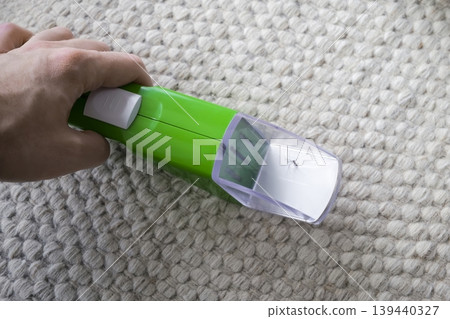 Insect catcher held by a hand against a textured carpet, presenting a simple everyday home solution for safe insect handling. 139440327
