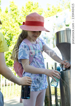 Eco friendly kids using public water station on a hot sunny day Eco friendly kids using public water station on a hot sunny day 139440415