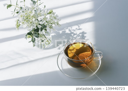 A peaceful tea time with morning light, tea, and white flowers. 139440723