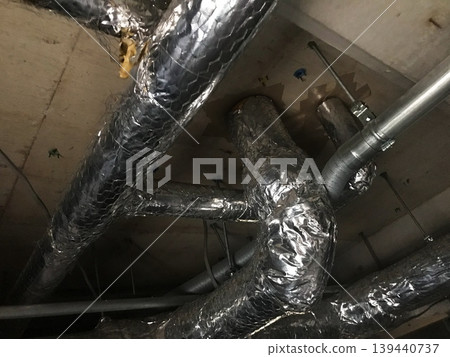Insulated ducts and pipes installed in the ceiling space of the building. 139440737
